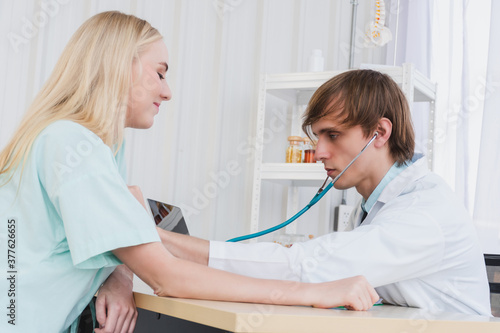 A doctor is examining the heartbeat of the patient