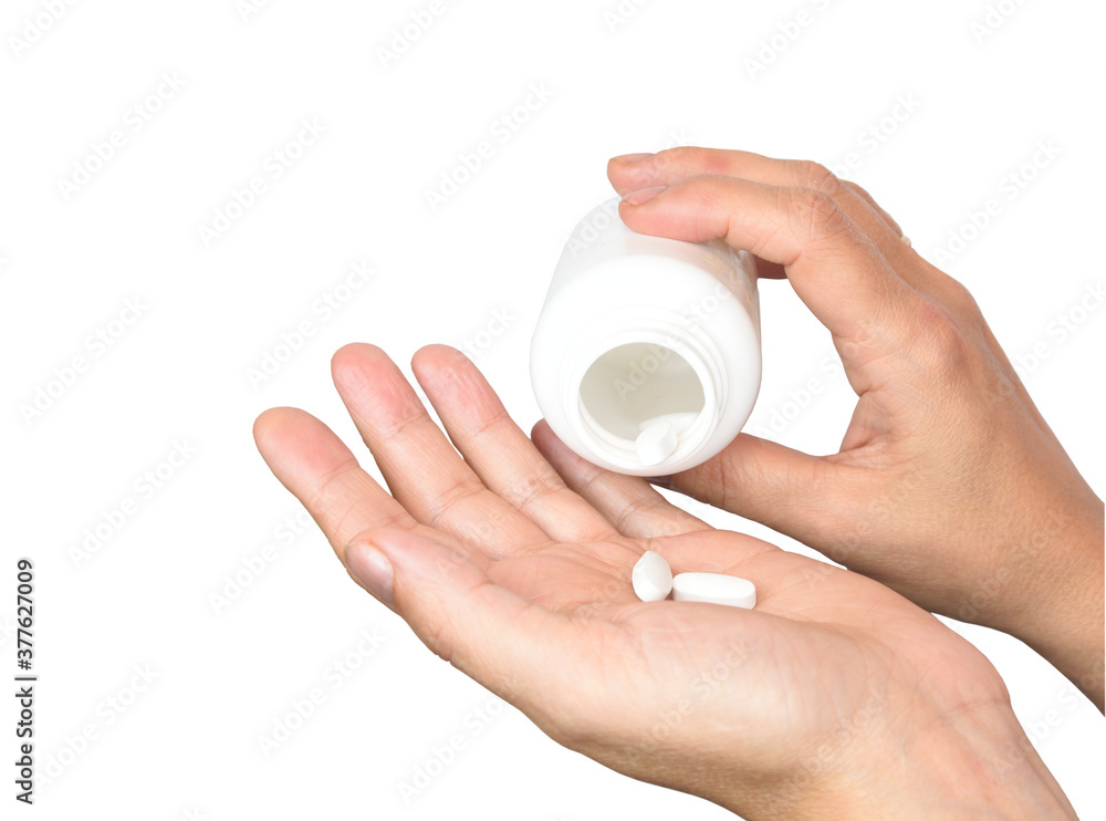 Female hands pouring vitamins from a white jar into the palm Female hands pouring vitamins from a white jar into the palm