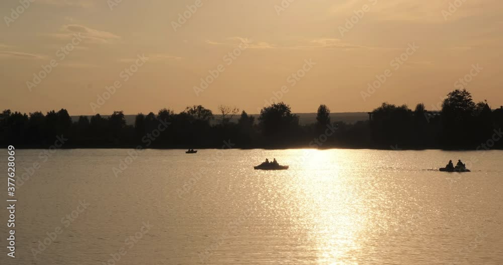 Calm natural video of a lake, river, canal with boats, coracle, paddle boats, coble, slalom, dory with people on a beautiful sunset with treason a background in 4k slow motion panorama, water shining Calm natural video of a lake, river, canal with boats, coracle, paddle boats, coble, slalom, dory with people on a beautiful sunset with treason a background in 4k slow motion panorama, water shining