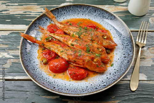 pesce gallinella di mare in salsa di  pomodori freschi photo