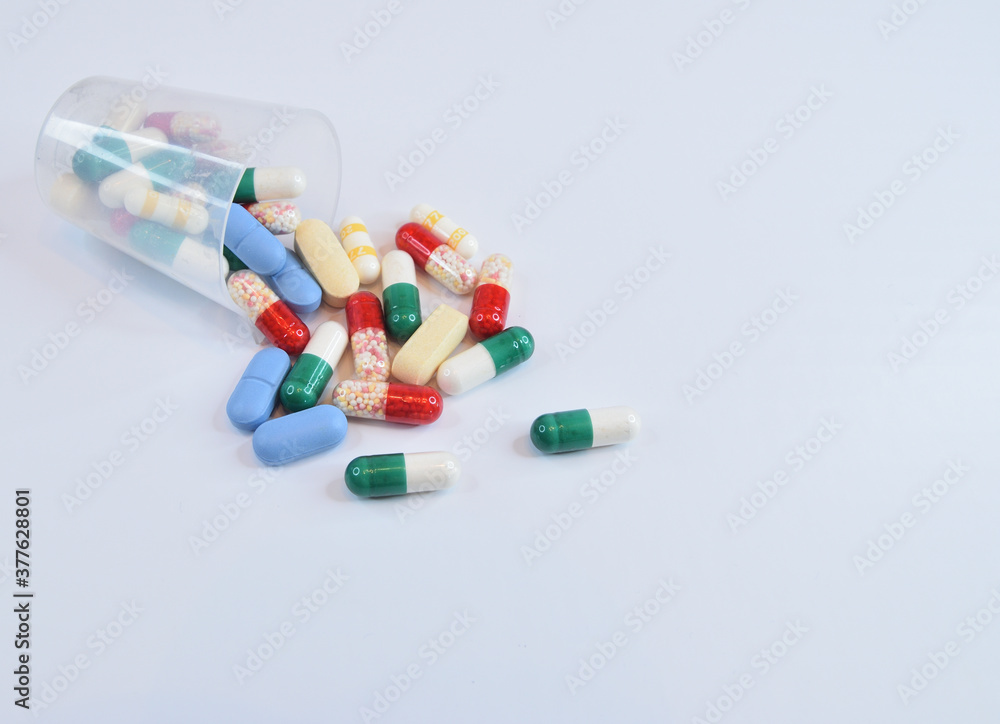 An overturned measuring cup for dispensing medicines with pills scattered around An overturned measuring cup for dispensing medicines with pills scattered around