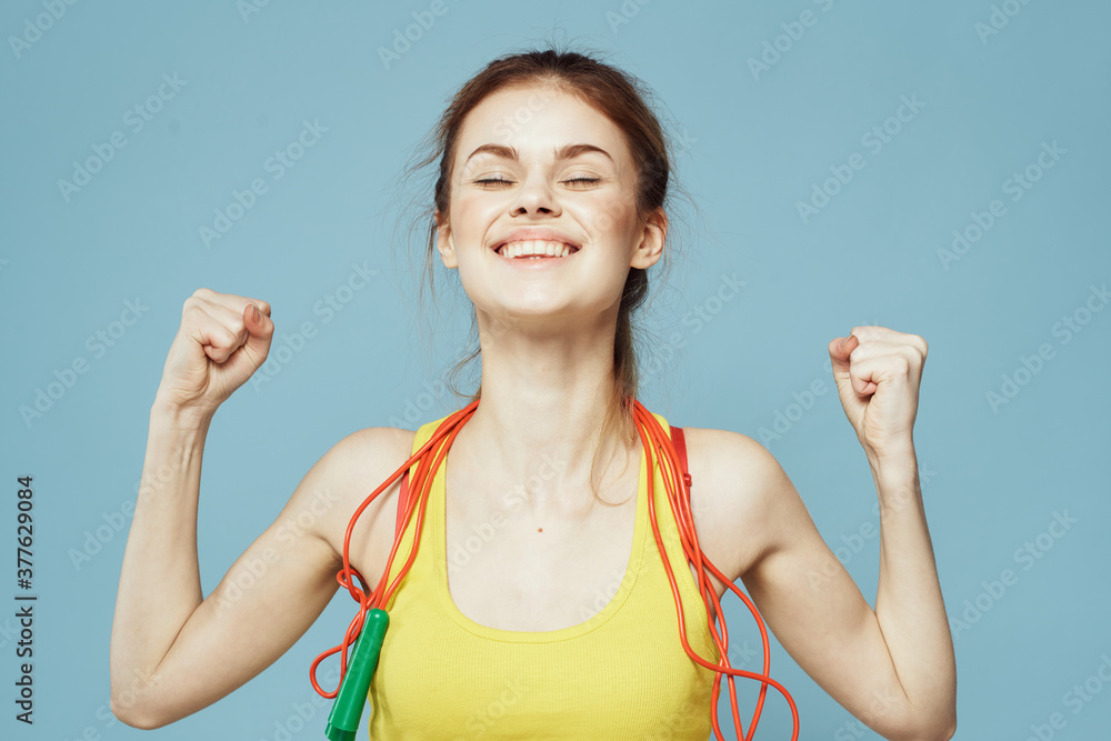 Woman with skipping rope sport exercise yellow tank top blue background Woman with skipping rope sport exercise yellow tank top blue background