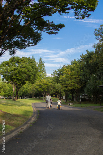 公園を自転車とベビーカーで散歩する日本人の親子 © kanahina