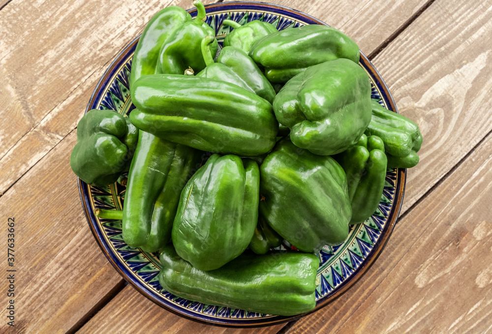 Large green peppers from the garden are in a plate on the table. Large green peppers from the garden are in a plate on the table.