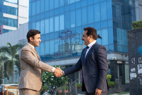 Photography Businessman and businesswoman shaking hands on city street