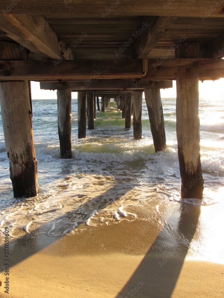 Calm sea waves under a wooden bridge. This image can be used for an article about dream interpretation. Being under the bridge in a dream means that someone is unable to overcome problems in life.
