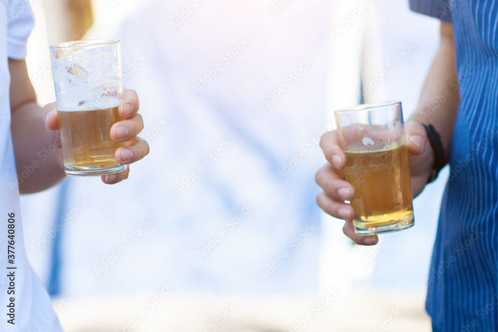 Two young men carried drinking glasses at an outdoor party in the backyard. Two young men carried drinking glasses at an outdoor party in the backyard.