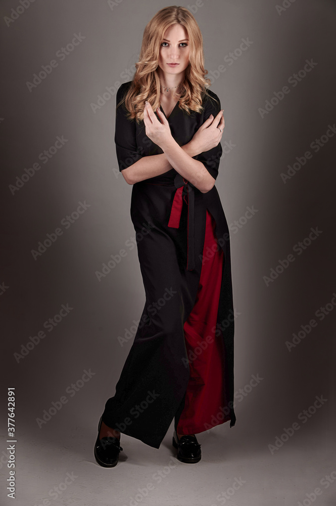 Fototapeta premium A slender girl in black and red clothes on a gray background.