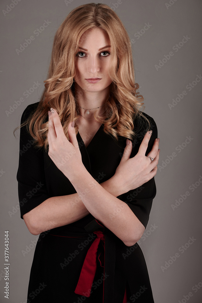 Fototapeta premium A slender girl in black and red clothes on a gray background.
