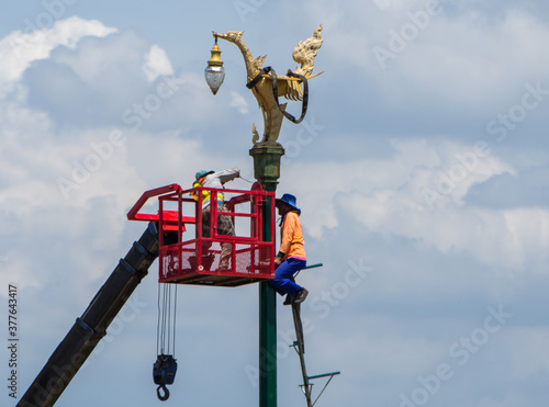 A mechanic is on a cable car to fix a light on a pole at Hong on the Aksa Road, Thailand, 24-08-2020.
