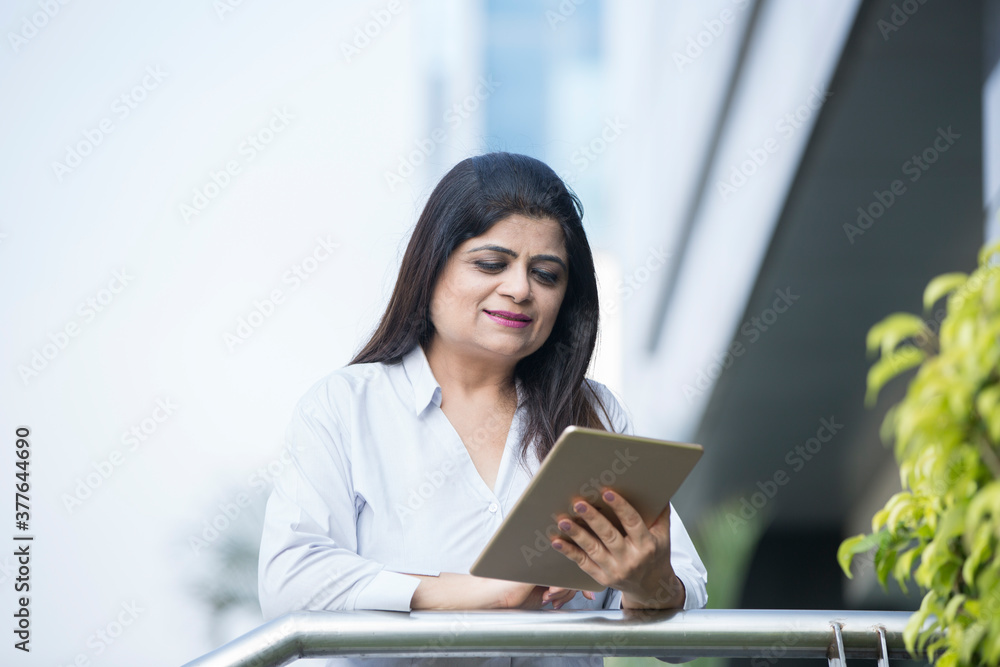 Happy businesswoman holding digital tablet outside office building Happy businesswoman holding digital tablet outside office building