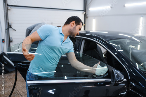 Male worker cleans car for tinting, tuning service
