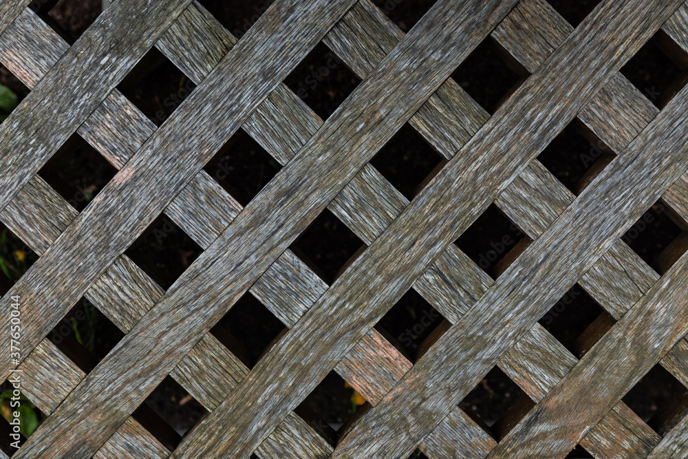Brown wood fence texture with diagonal bars or planks and black square gaps between them Brown wood fence texture with diagonal bars or planks and black square gaps between them