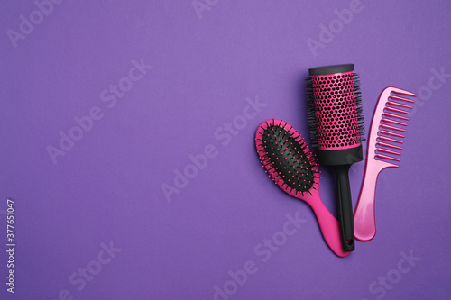 Modern hair comb and brushes on purple background, flat lay. Space for text