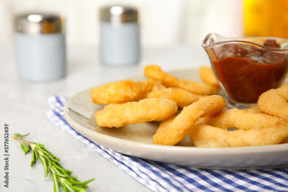 Delicious crunchy fried onion rings and rosemary on light table, closeup Delicious crunchy fried onion rings and rosemary on light table, closeup