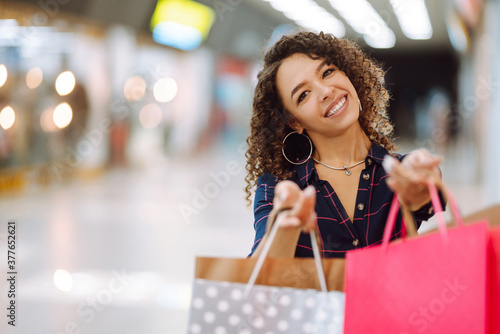 Smiling woman with shopping bags enjoying shopping in the mall.Young woman with packages after shopping. Purchases, black friday, discounts, sale concept.