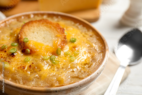 Tasty homemade french onion soup served in ceramic bowl, closeup