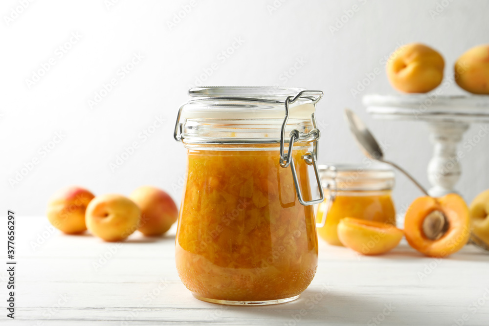 Jar of apricot jam and fresh fruits on white wooden table Jar of apricot jam and fresh fruits on white wooden table