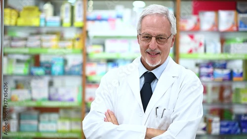 Senior pharmacist smiling and folding arms in his store