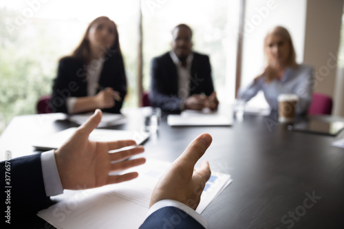 Back view close up of male applicant sit at desk talk at interview with potential employers. Confident motivated man job candidate or business partners discuss project with coworkers at briefing.