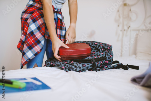 School girl putting school supplies into backpack