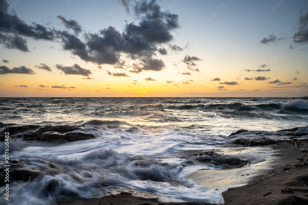 Idyllic view of waves on sand at sunset