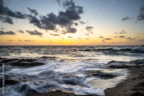 Idyllic view of waves on sand at sunset
