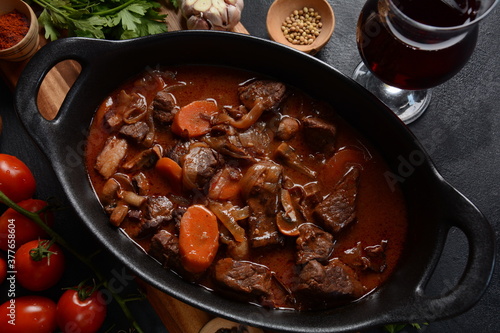 Beef Bourguignon in a pan. Stew with red wine ,carrots, onions, garlic, a bouquet garni, and garnished with pearl onions, mushrooms and bacon. French cuisine- regional recipe from Burgundy