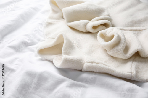 Warm fleece sweater on white crumpled fabric, closeup