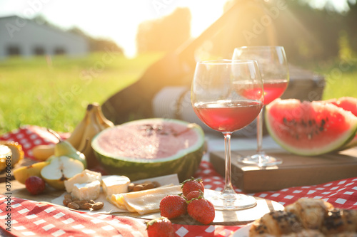 Picnic blanket with delicious food and drinks outdoors on sunny day, closeup