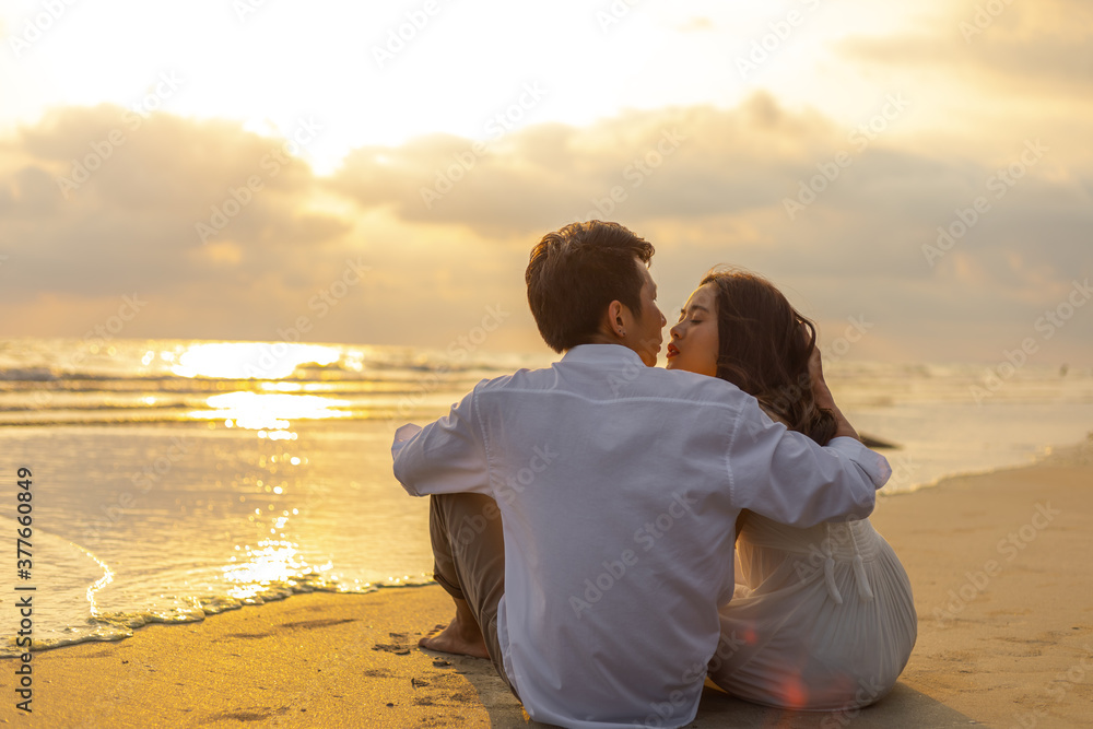 Couple in love watching sunset together on the beach travel summer holidays. People romance concept.