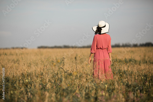 young woman in dress and hat in summer field