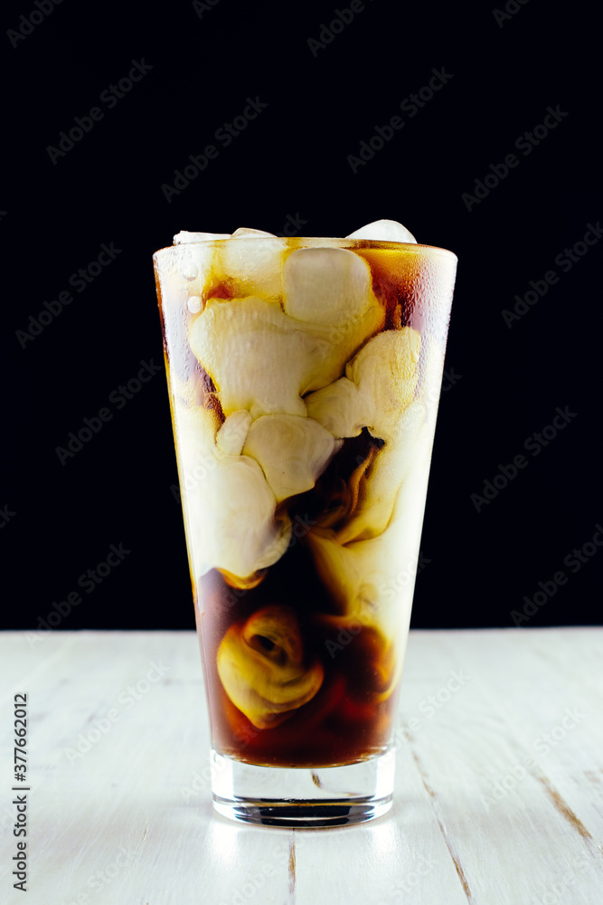 Cold brew coffee with milk in glass on dark background Cold brew coffee with milk in glass on dark background