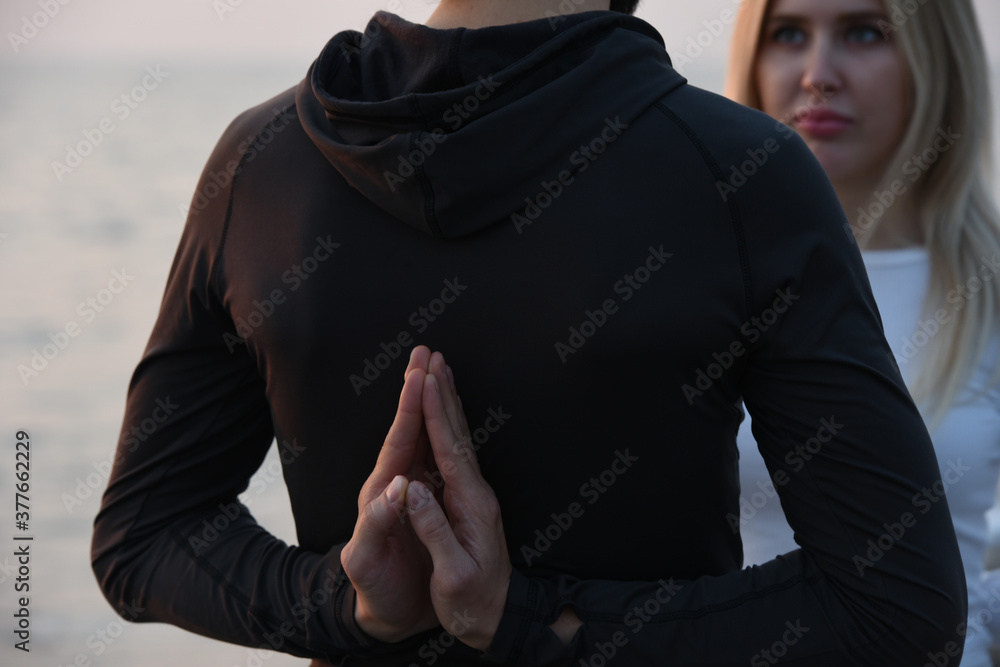 a guy and a girl are sitting on the beach in the lotus position namaste hands