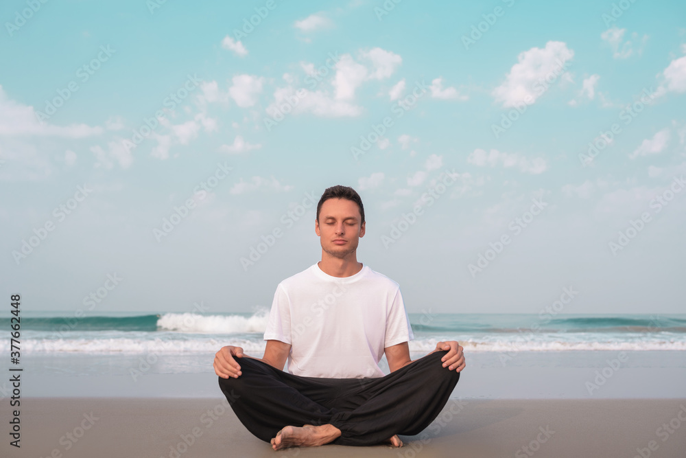 the guy sits on the seashore in the lotus position and meditates. the guy sits on the seashore in the lotus position and meditates.