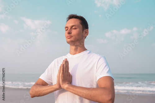 happy guy sits on the seashore and meditates.
