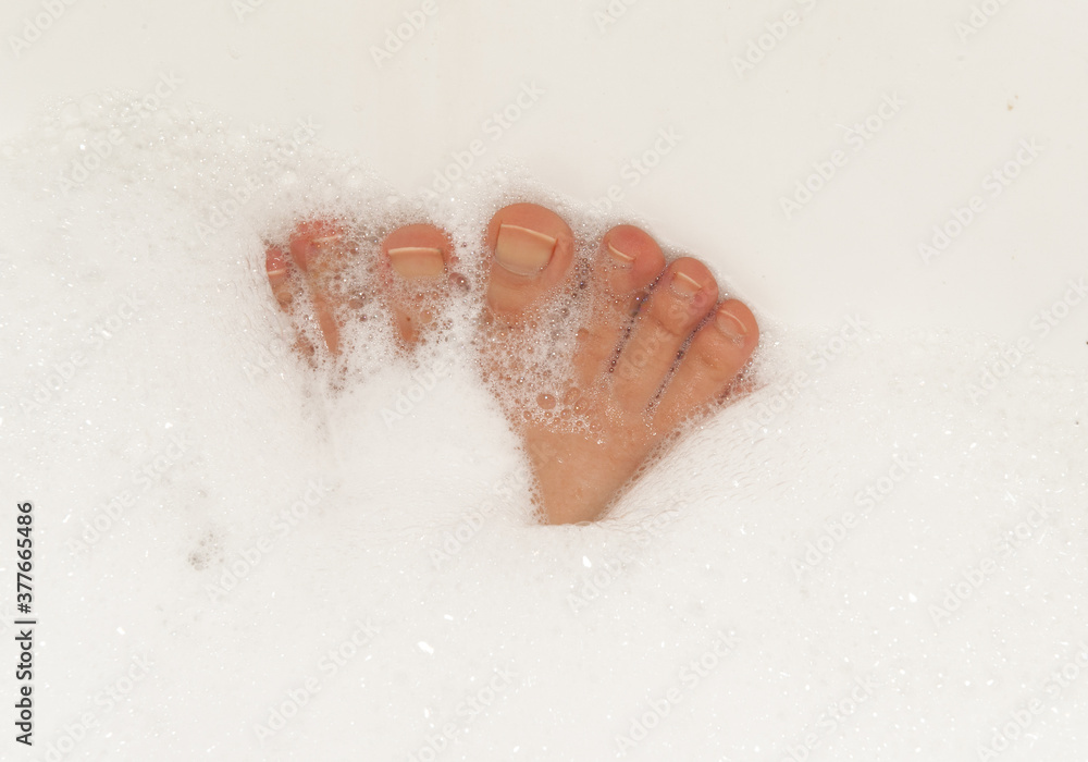 Fototapeta premium Female feet in soapy foam