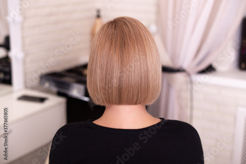 
Female back with short straight natural blonde hair in hairdressing salon