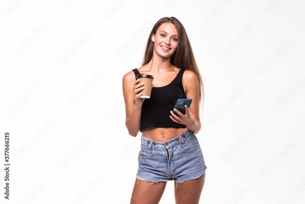 Young woman in formal wear standing with smartphone and takeaway coffee in hands isolated over white background