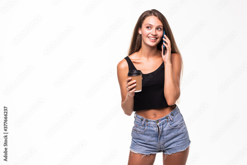 Fototapeta premium Young woman talking on mobile phone while having coffee on white background