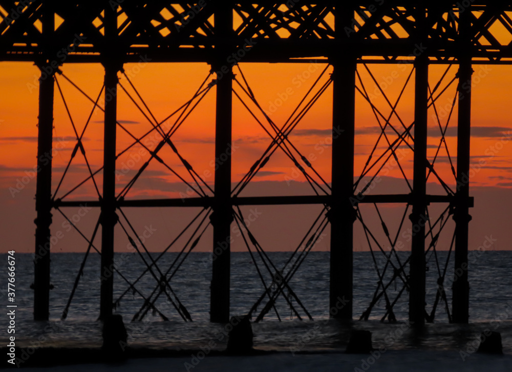 Fototapeta premium Sunset viewed through the structure of a pier