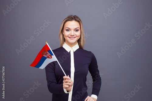 Immigration and the study of foreign languages, concept. A young smiling woman with a Serbia flag in her hand.