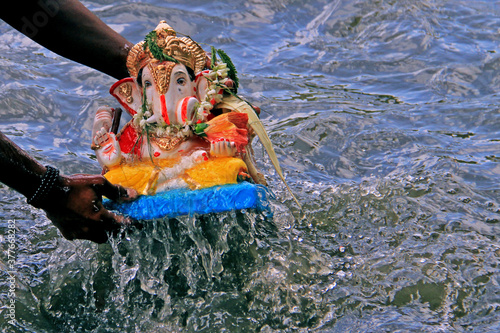 An idol of Lord Ganesha being immersed in water in Maharashtra at Ganesh Visarajan. photo