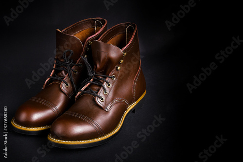 Fashionable mens leather brown shoes on black background.