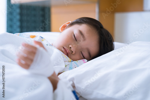 Asian cute little boy is sleeping on the sickbed with saline intravenous on hand. and the face with tears in the patient room in hospital selective focus. Healthcare medical and people concept.