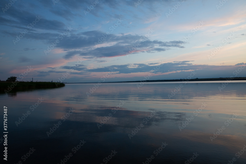 Fototapeta premium colored sunset over the river, with sky reflection