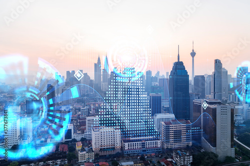 Hologram of abstract technology glowing icons  panoramic cityscape of Kuala Lumpur at sunset  Malaysia  Asia. The concept of worlds technological changes. Double exposure.