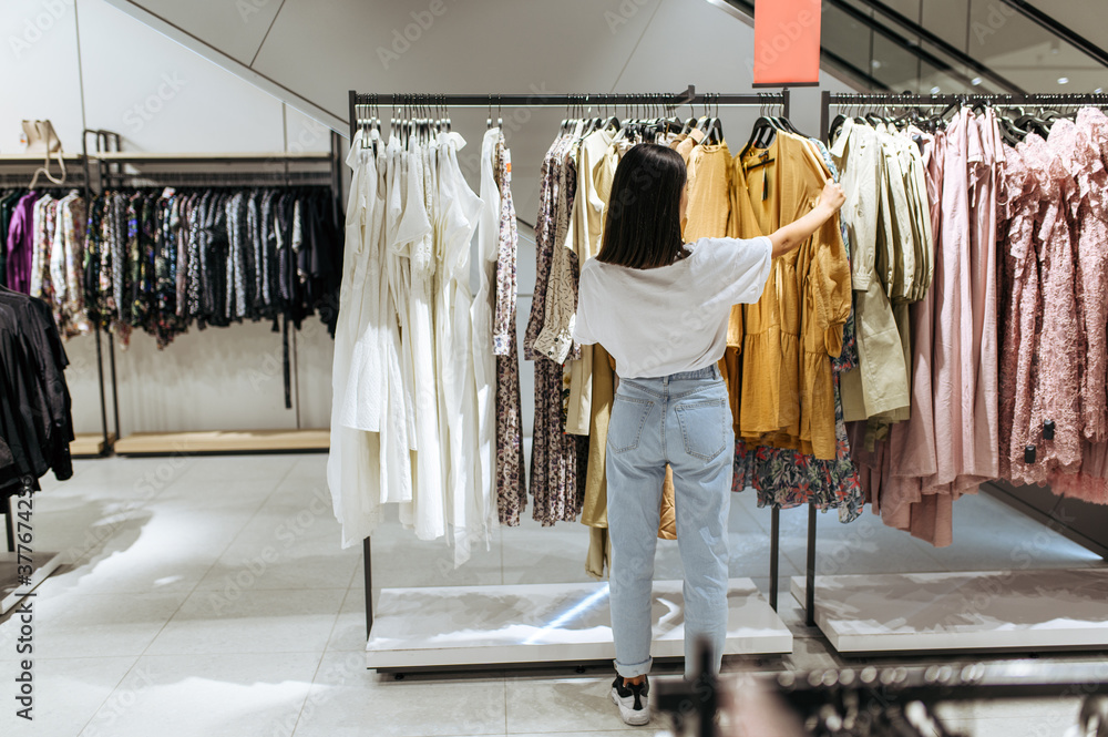 Woman choosing elegant dress in clothing store