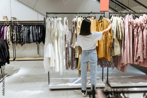 Obraz na plátně Woman choosing elegant dress in clothing store