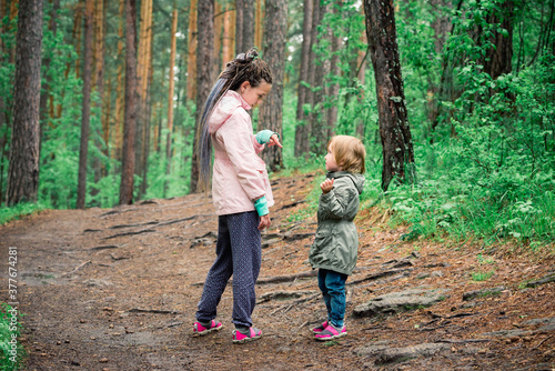 Beautiful little sister girls on forest clearing among the trees. © Evgenii